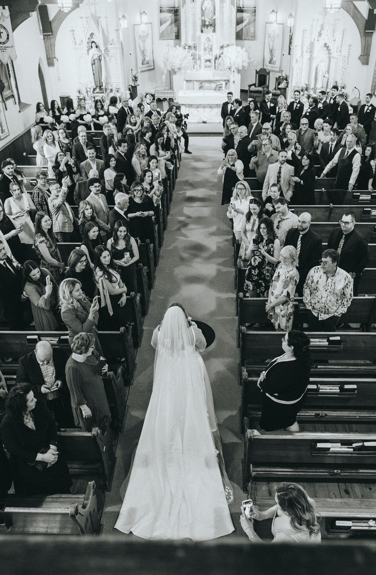 Wedding ceremony procession in traditional church with guests in pews.