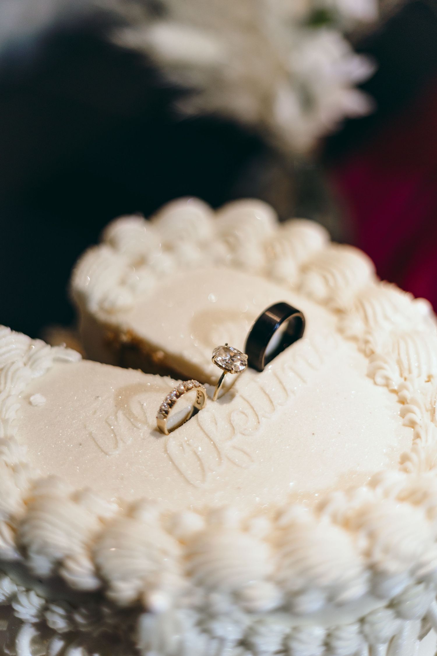 Detail shot of a white wedding cake with intricate piping and decorative elements.