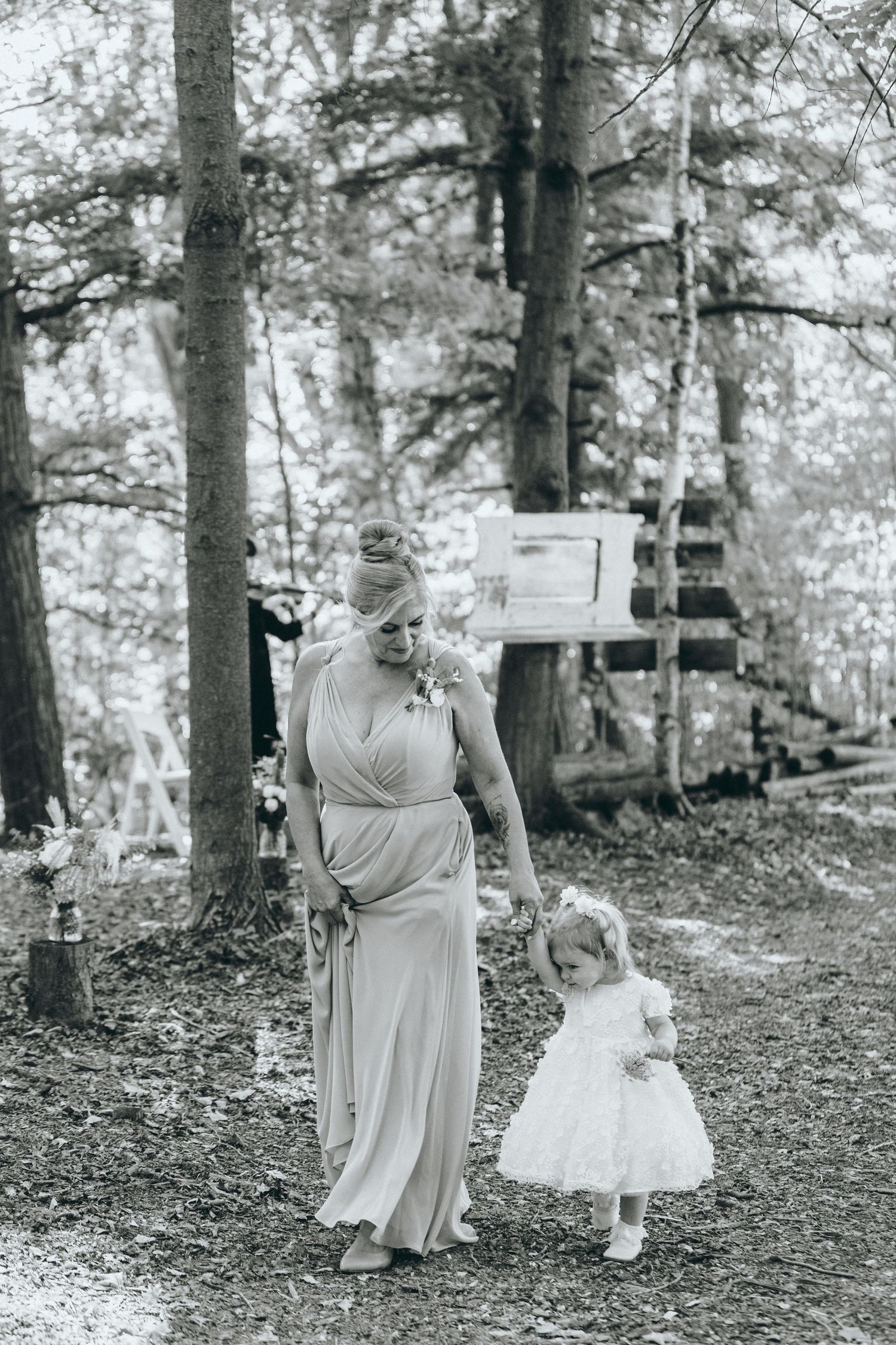 A tender moment captured in black and white between two figures in a wooded setting.