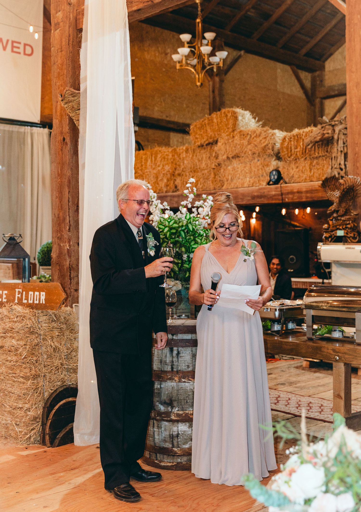 Wedding toast moment in rustic venue with exposed brick walls and elegant white draping.