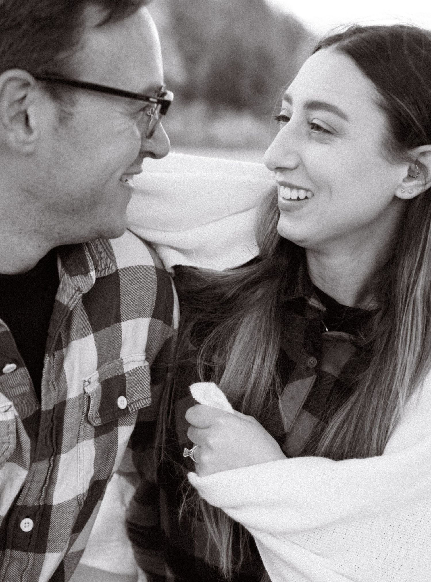 Black and white portrait of couple sharing intimate moment outdoors.