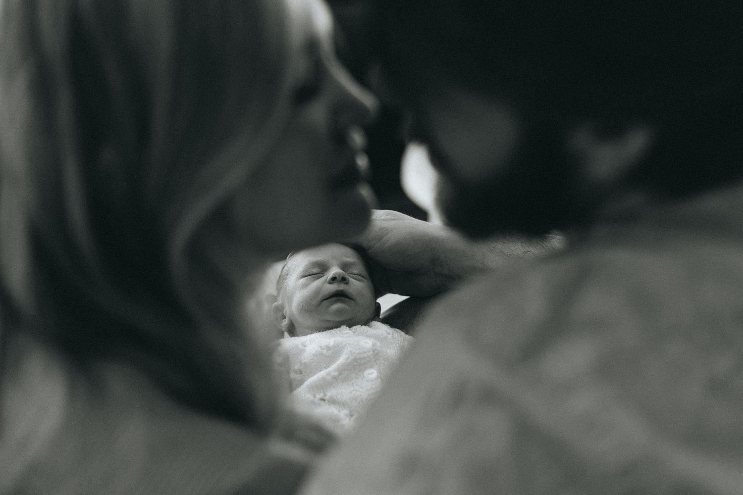 Black and white image of a newborn baby in a soft, intimate setting.