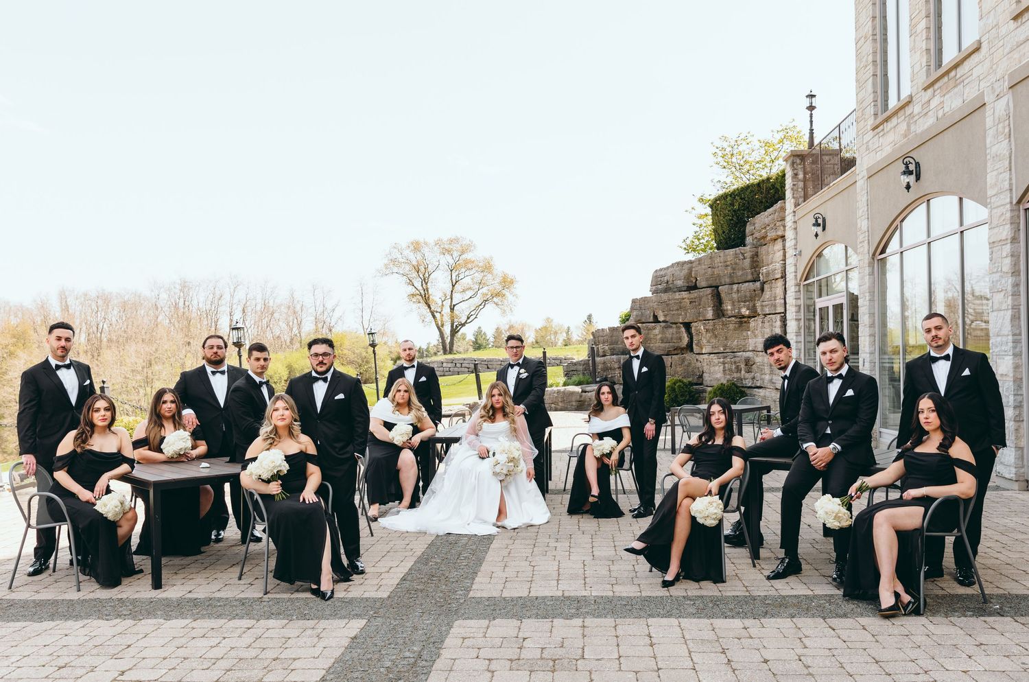 Wedding party relaxing on outdoor stone steps in formal attire.