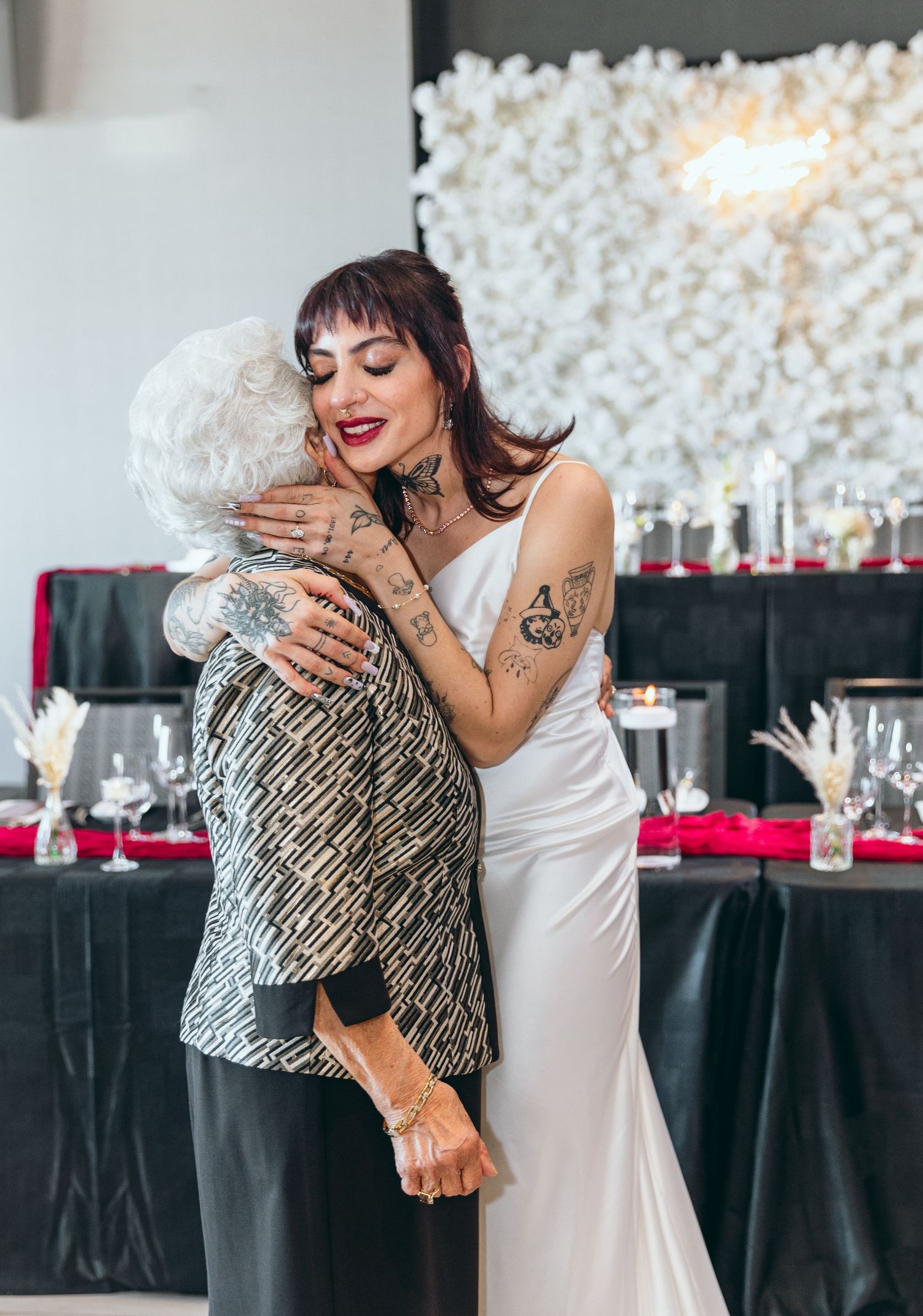 Emotional wedding moments shared between bride and guest in front of decorated reception area.