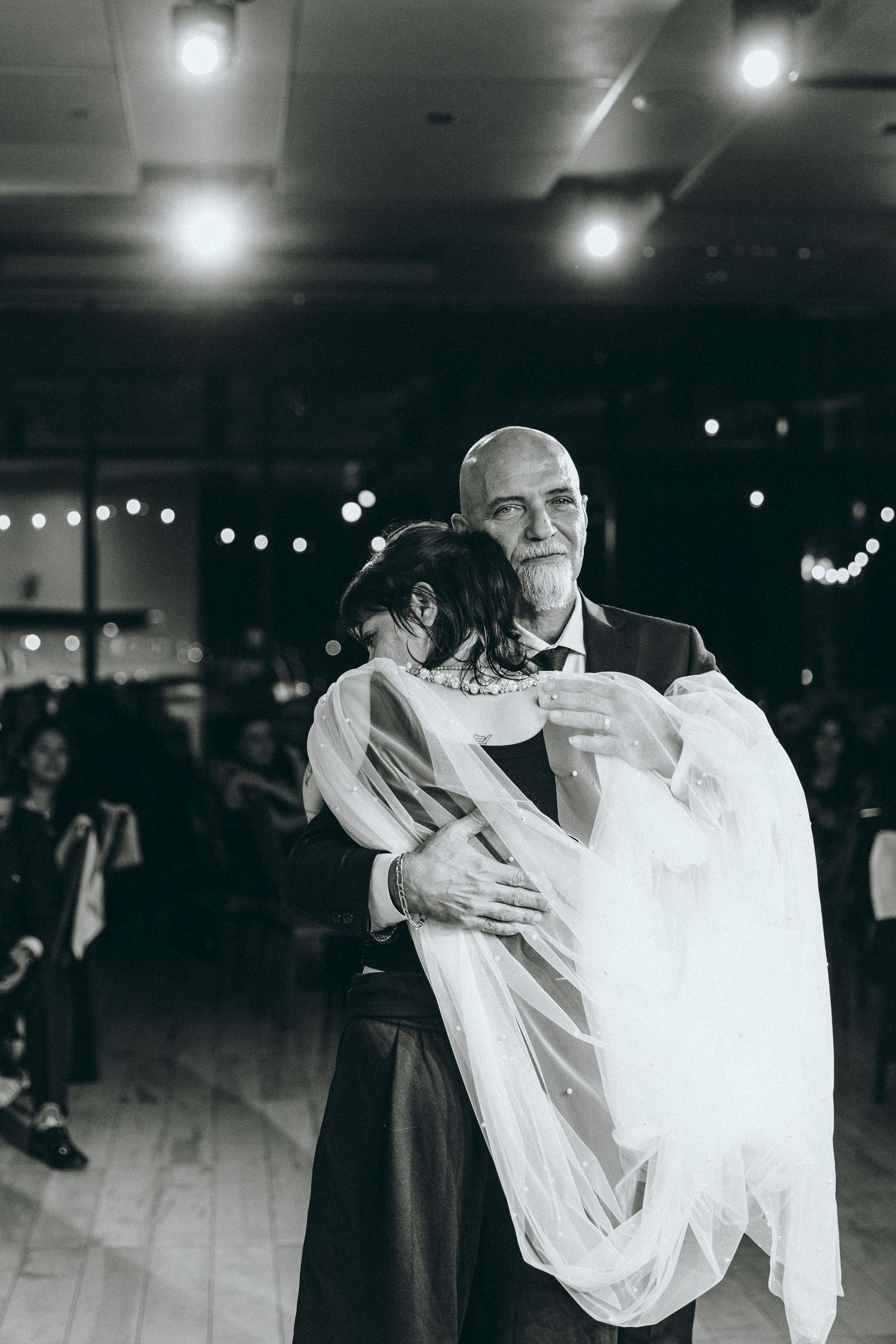 Black and white photo of couples dancing during an intimate wedding reception moment.