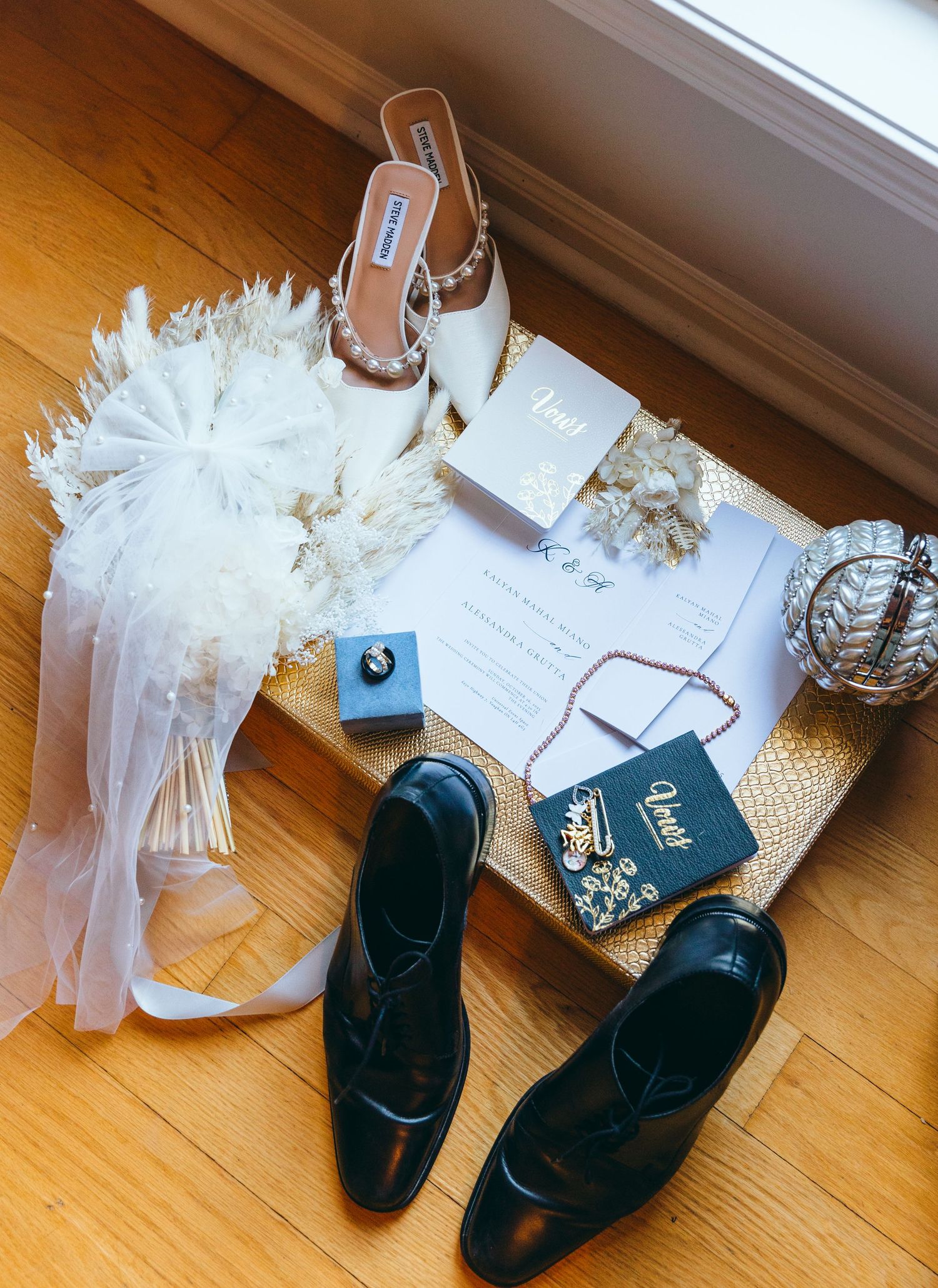 Black dress shoes and white tulle decorations arranged on a hardwood floor.