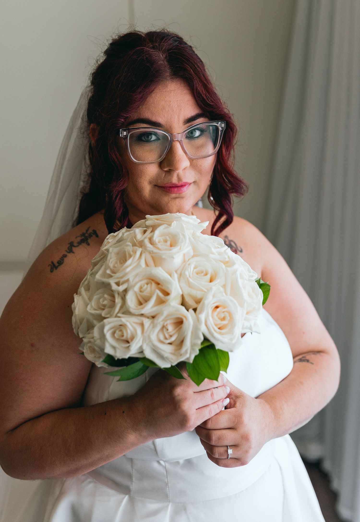 Person in white wedding dress holding classic white rose bouquet.