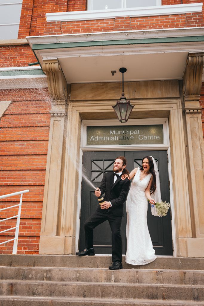 Wedding couple poses dramatically on steps outside a brick administrative building.