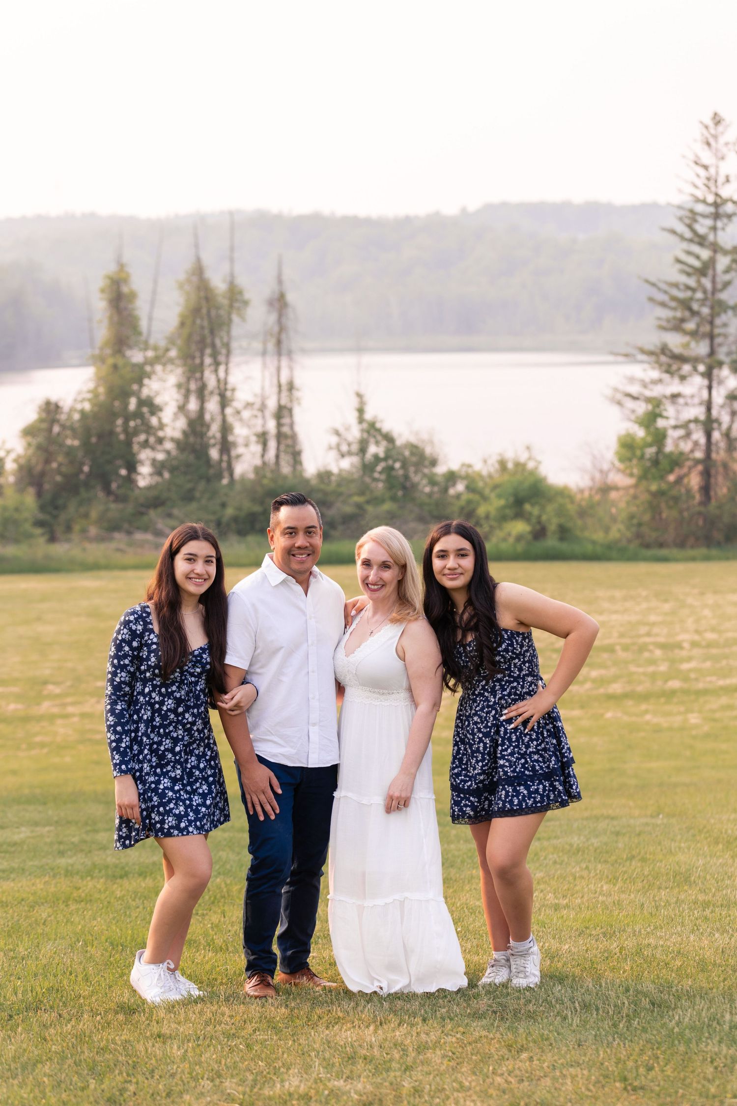 Group photo session in a scenic meadow with water and trees in the background.