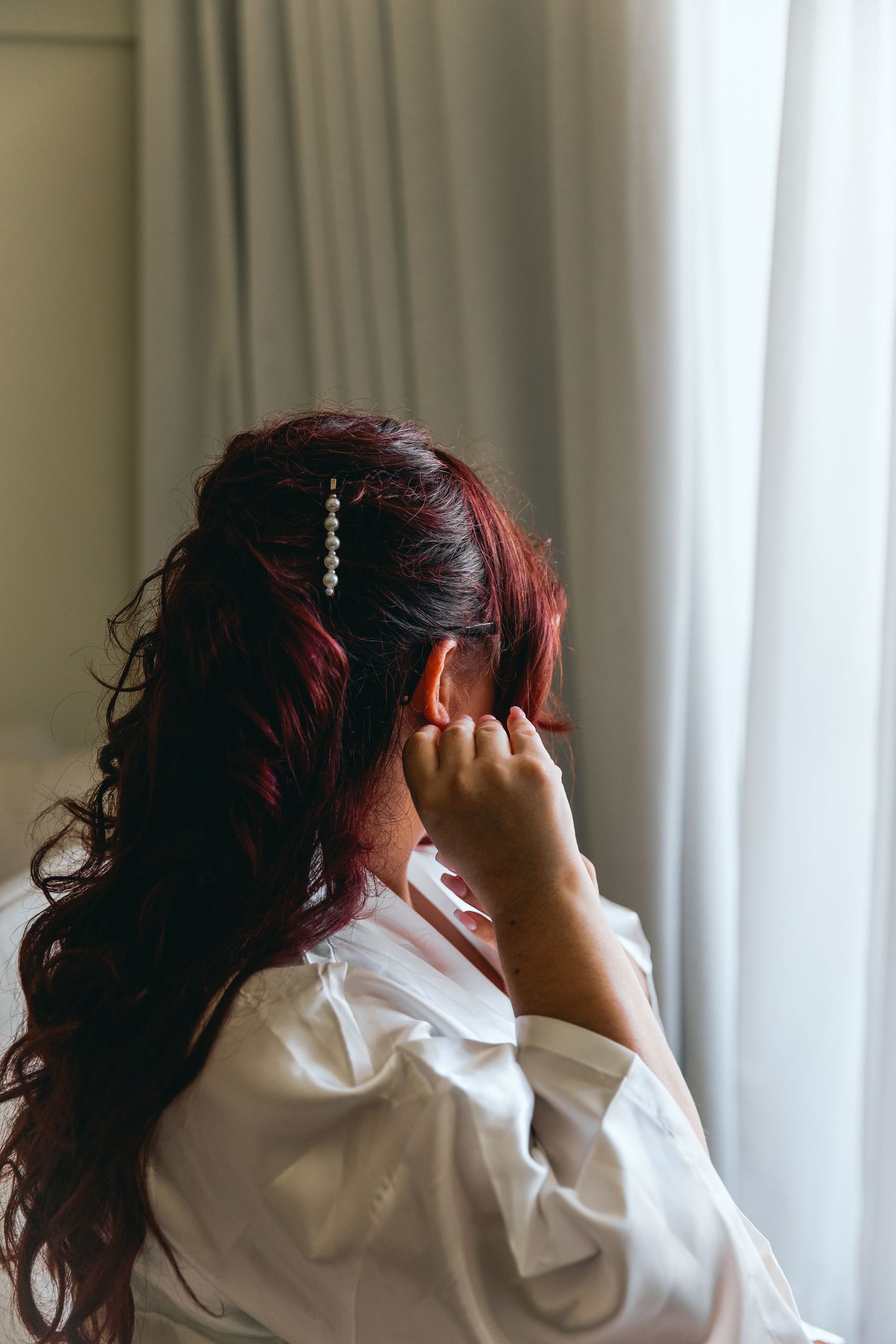 Person with styled hair in white shirt preparing for formal event.