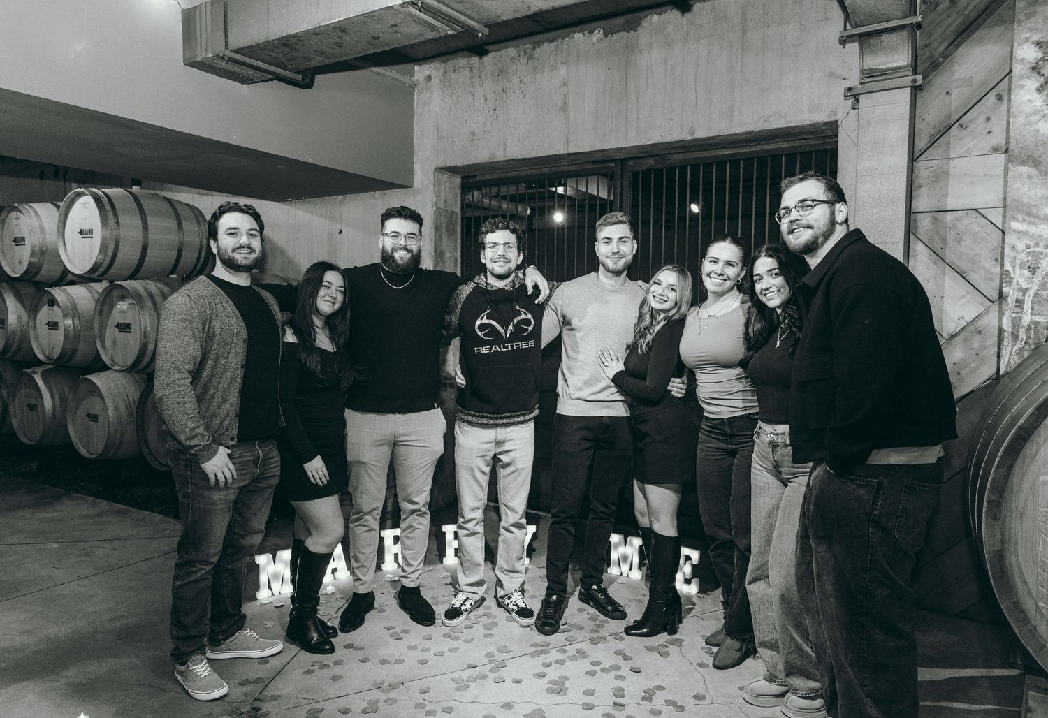 A group photo taken in a wine cellar with wine barrels in the background.