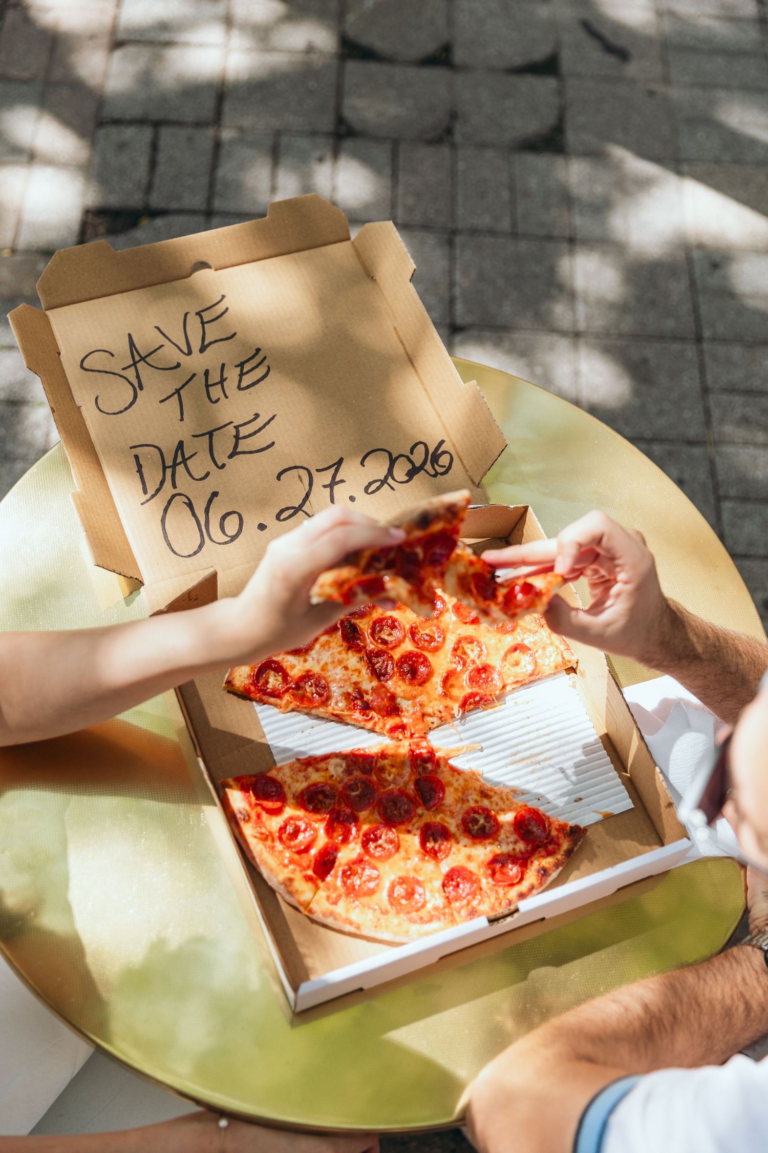A pizza box displays a save the date message with pepperoni pizza inside.