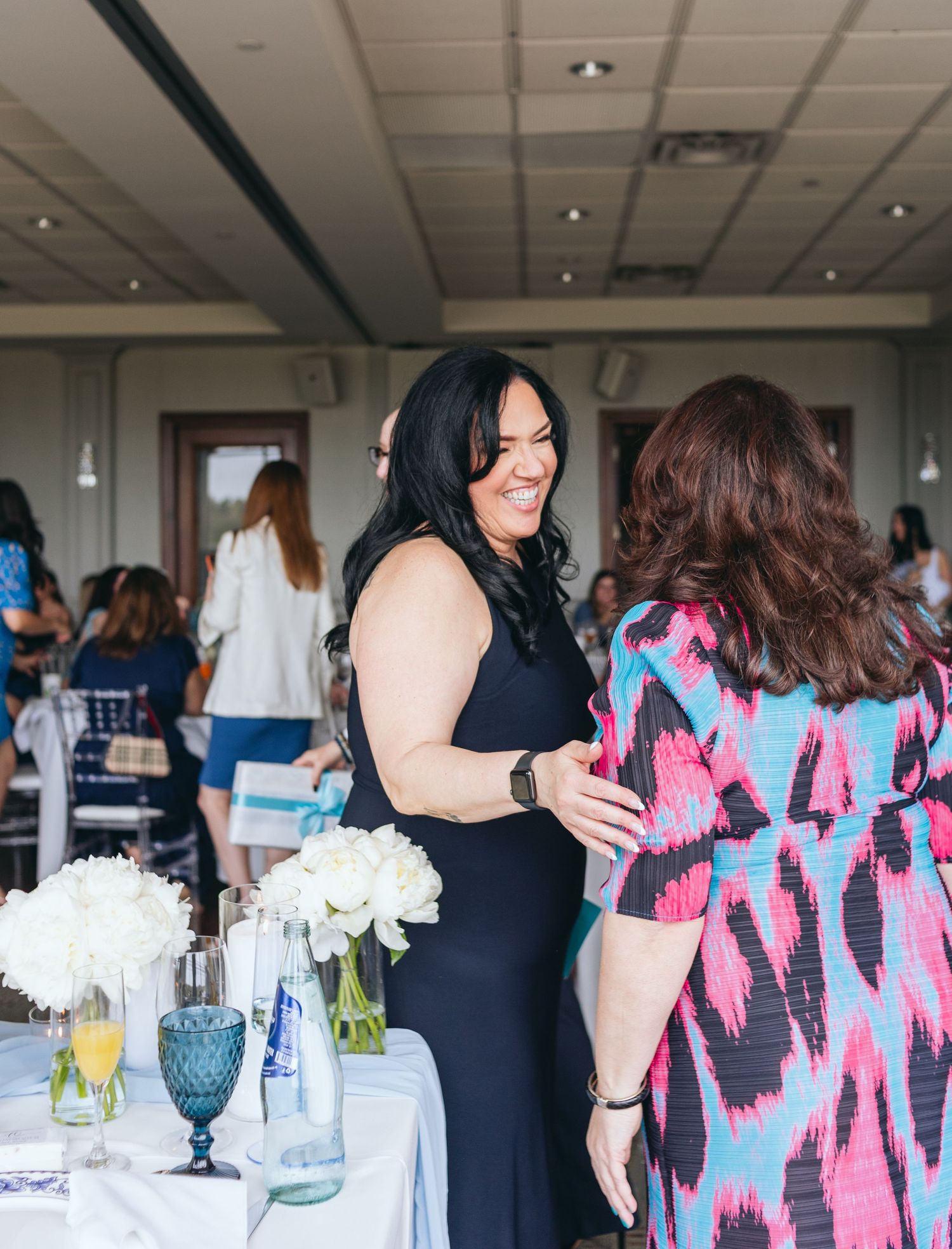 Wedding reception gathering with blue and pink color scheme and white floral decorations.