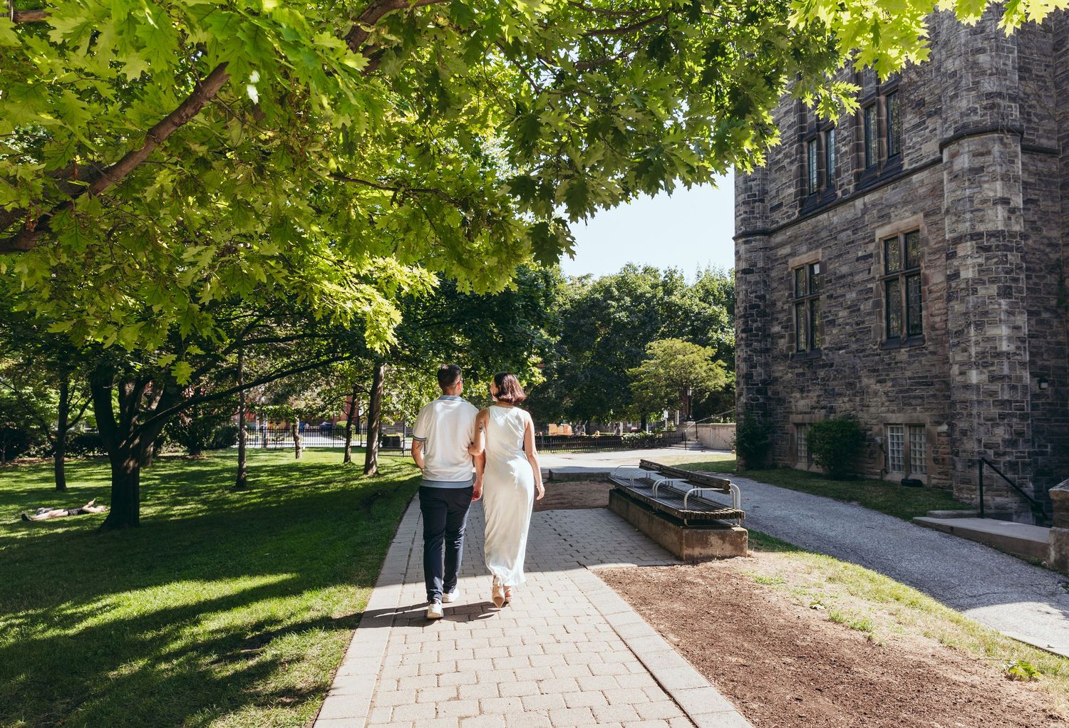 Tree-lined walkway leading to a stone Gothic architecture building on a college campus.