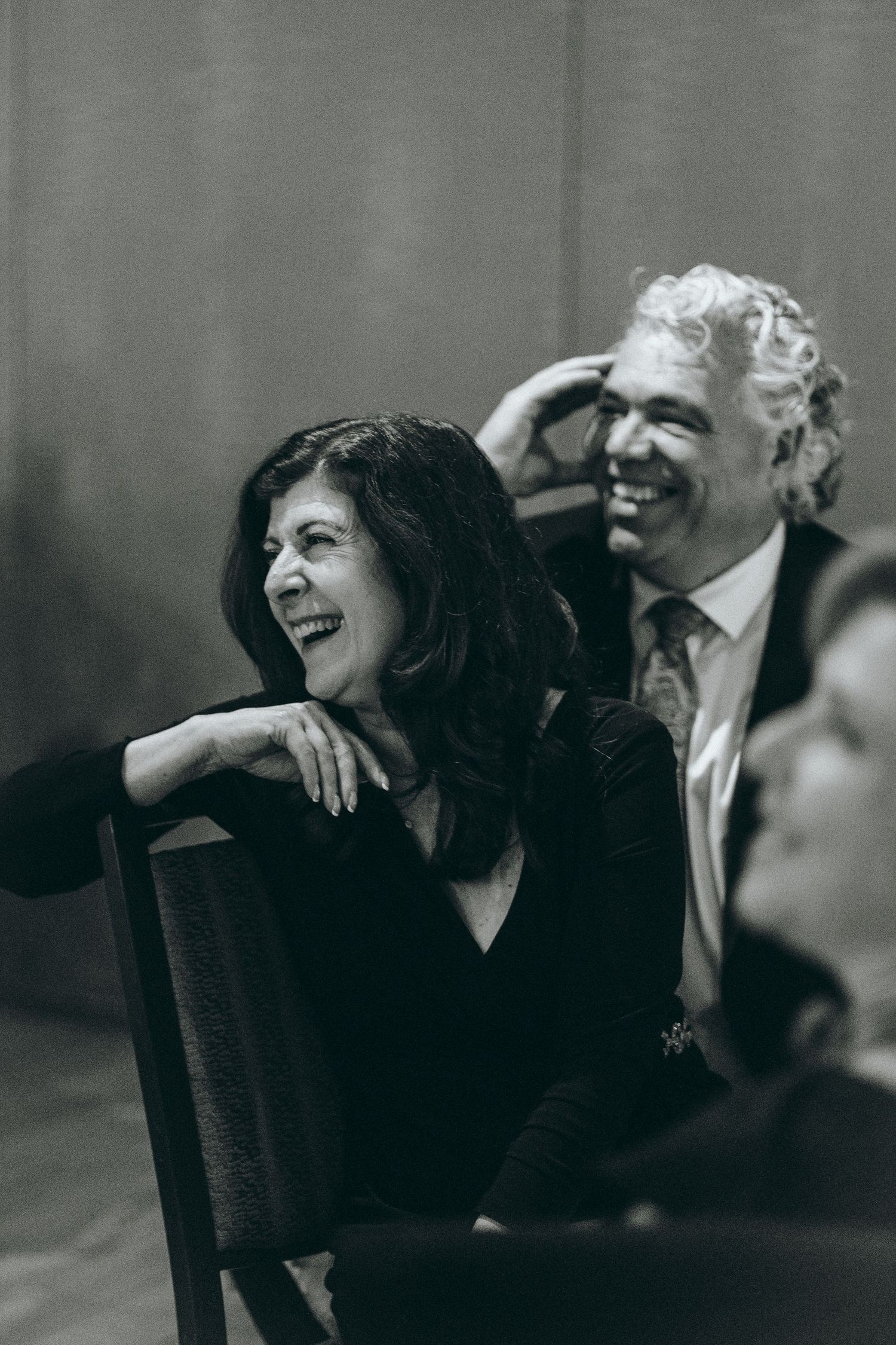 A candid black and white moment of laughter during a wedding celebration.