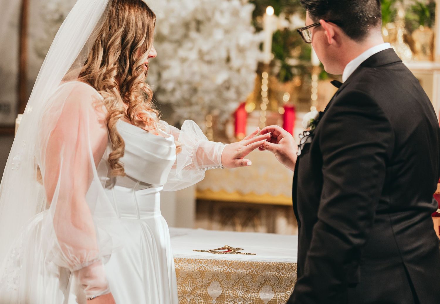 Close-up details of a wedding ceremony showing hands and formal attire.