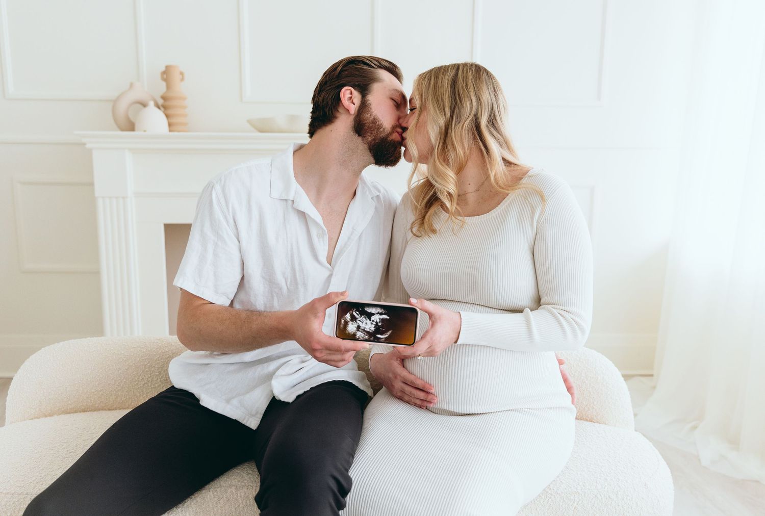 Expecting couple sharing tender moment while viewing ultrasound photo on bed.