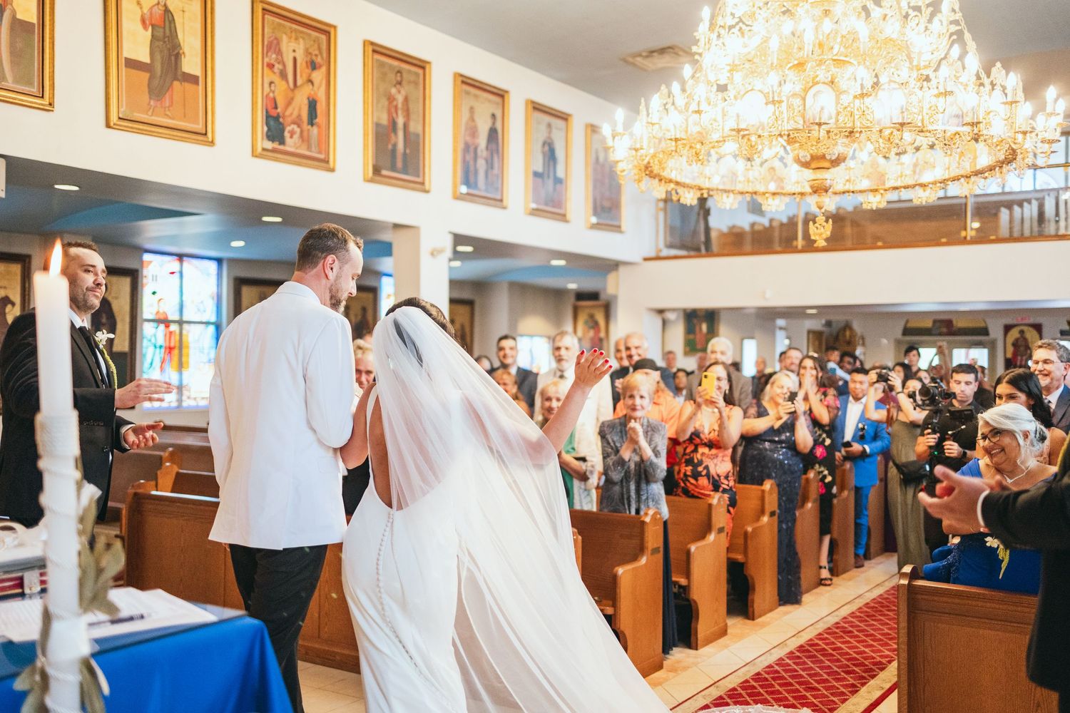 Wedding ceremony in grand church with crystal chandeliers and wooden pews.