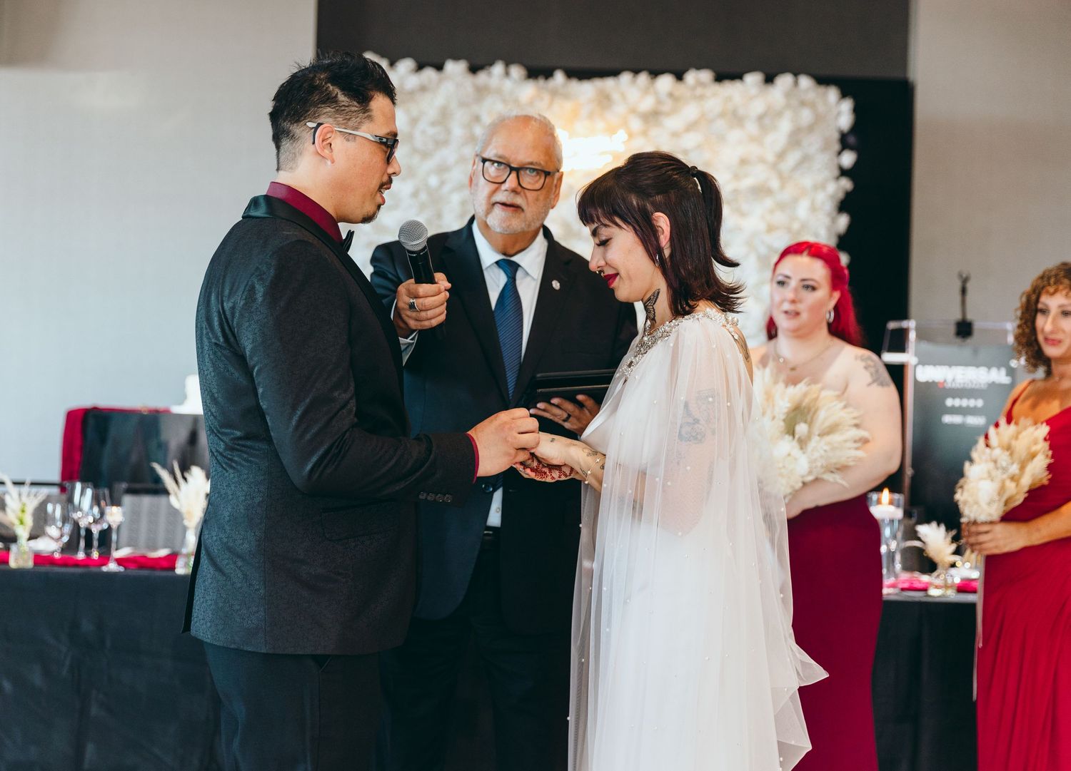 Intimate wedding ceremony moments captured in a contemporary space with white floral wall.