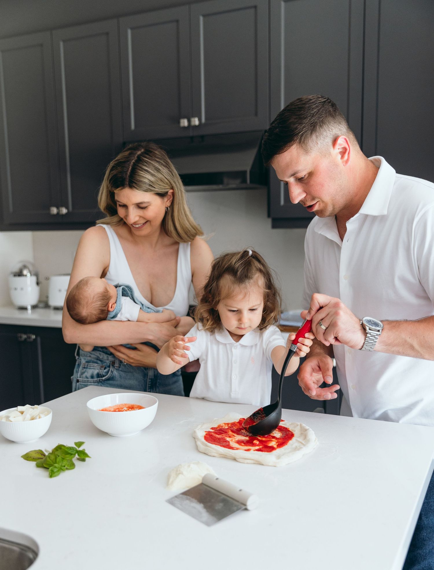 Family preparing food together at a white kitchen counter with fresh ingredients.