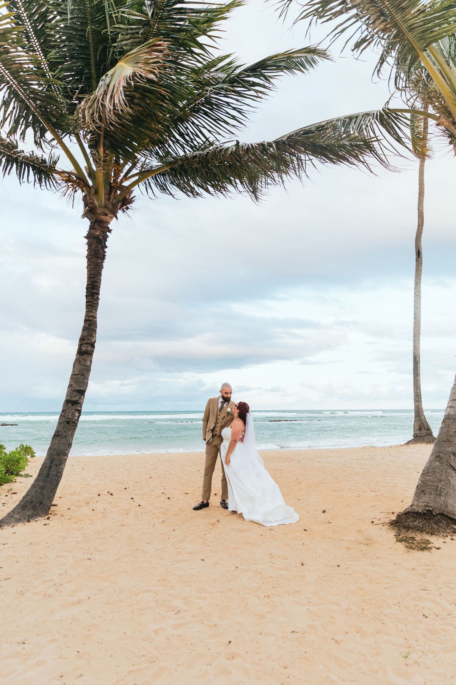 Palm trees line a sandy beach where a wedding ceremony takes place.