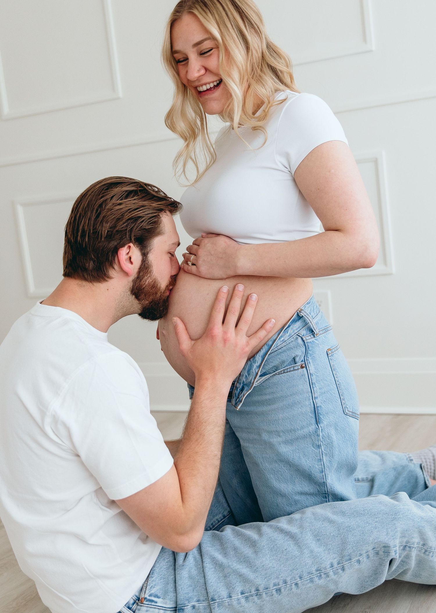 Intimate maternity photography showing tender moments between couple on floor.