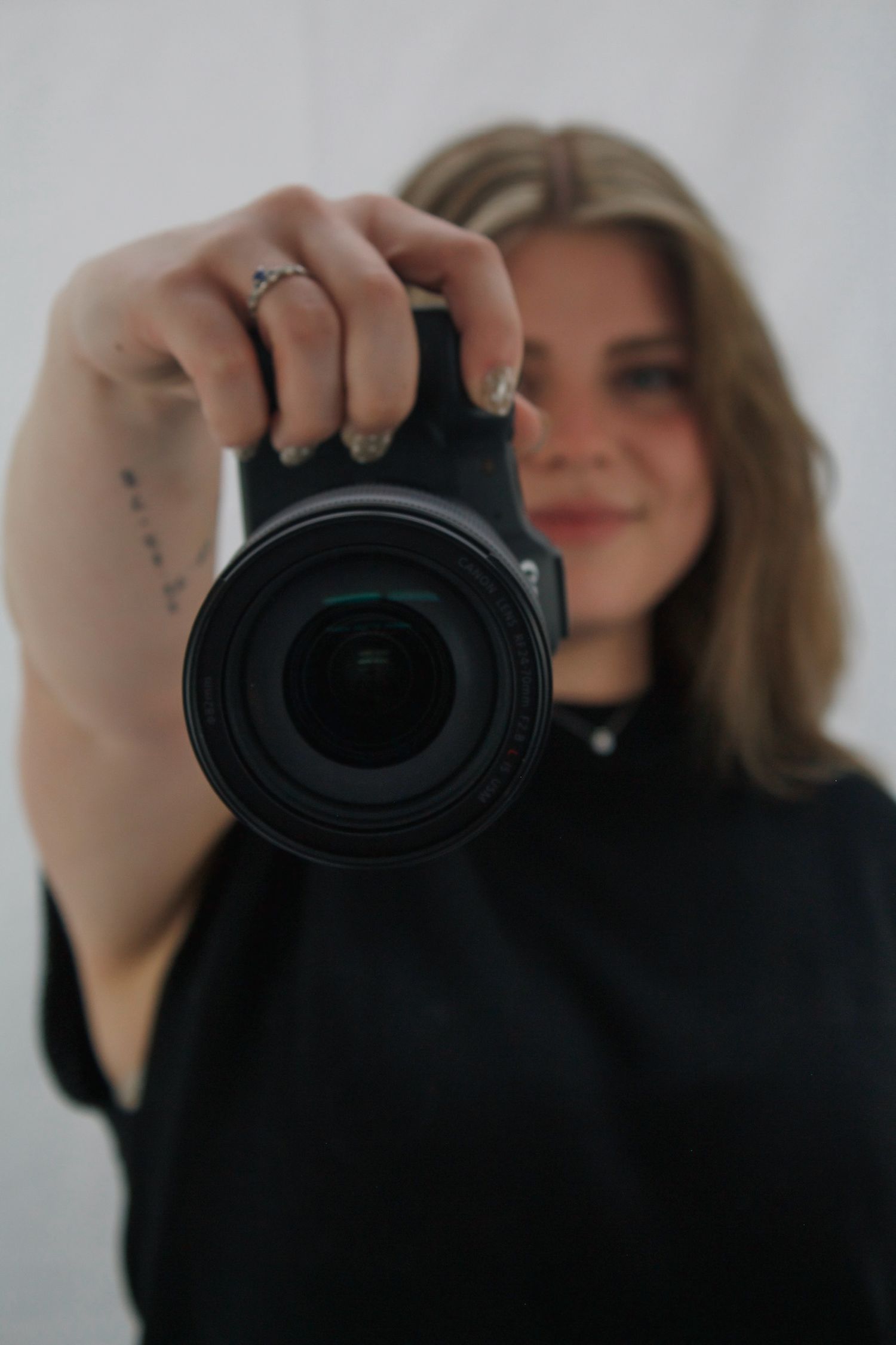 Photographer holding a camera with lens facing forward in a studio.