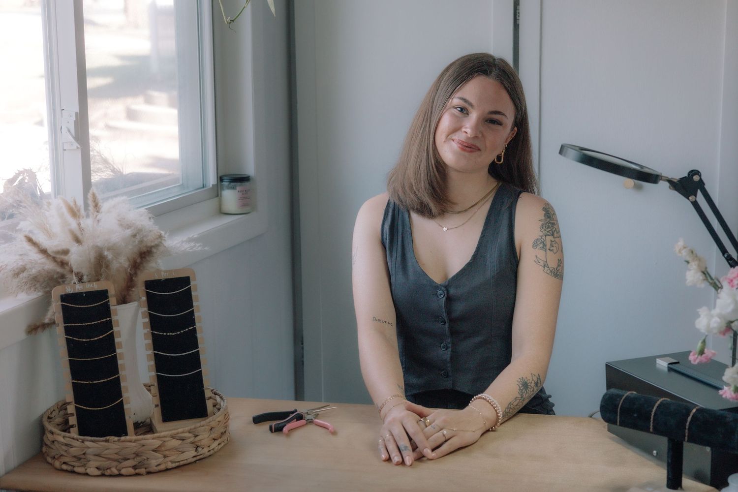 Female nail technician smiling at camera while seated at her salon workstation.