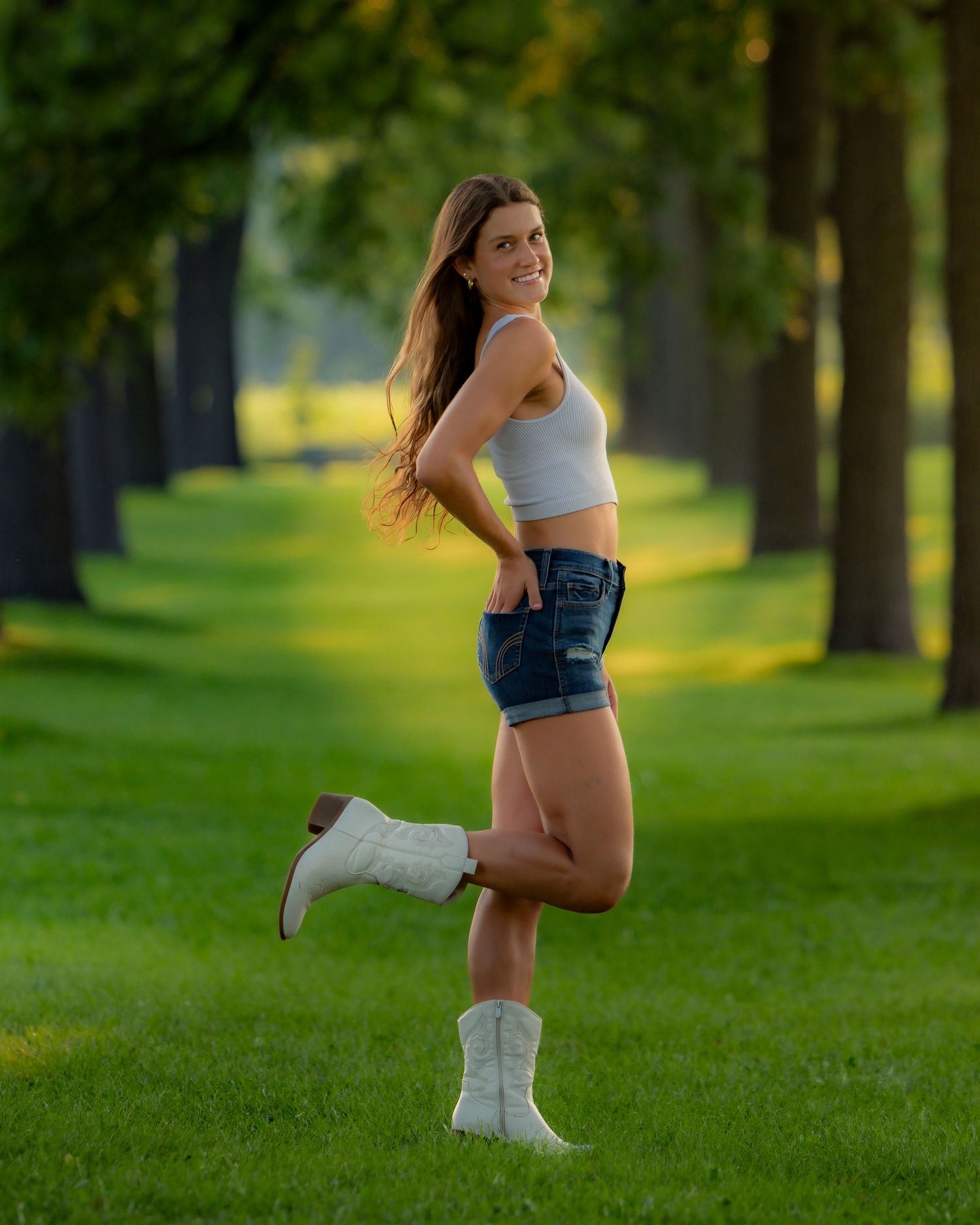 Person in athletic wear poses on green grass field during outdoor photoshoot.