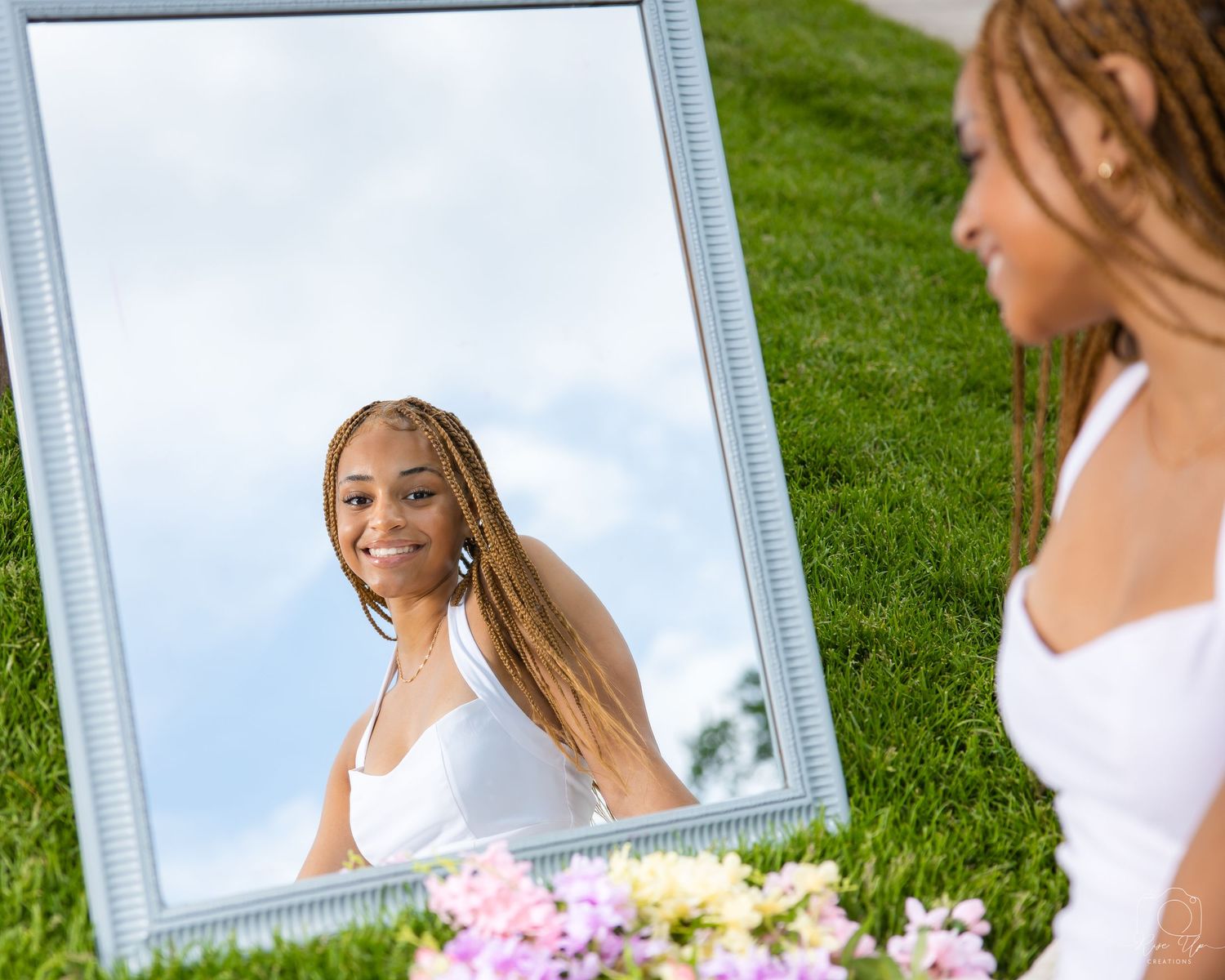 Outdoor graduation photos with mirror prop and pink flowers on green grass.
