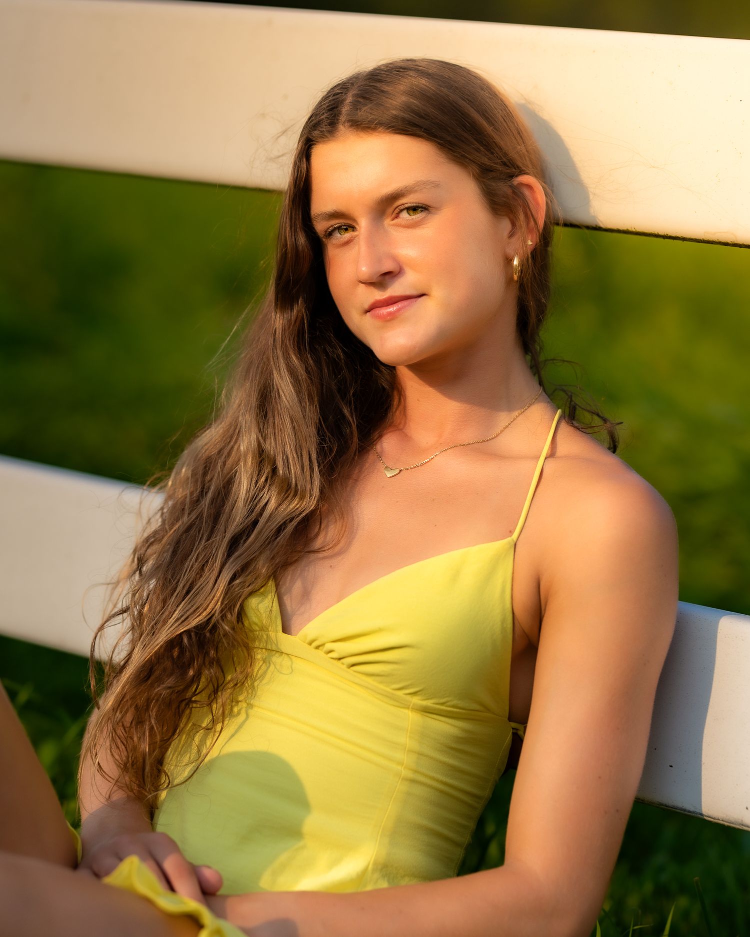 Golden hour portrait session featuring a yellow sundress against a rustic white fence.