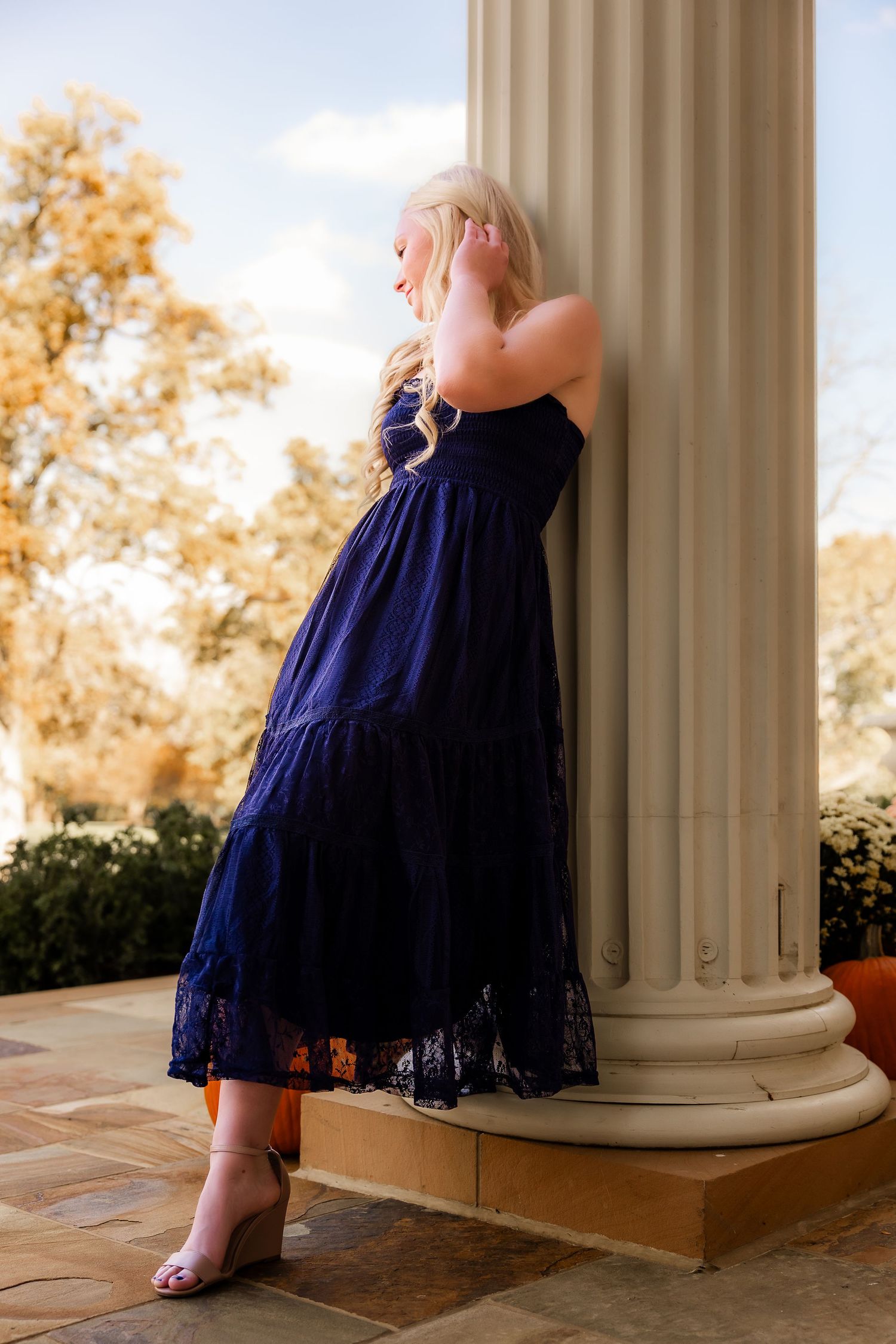 A series of photos showing a navy blue lace dress against white columns with autumn trees in the background.