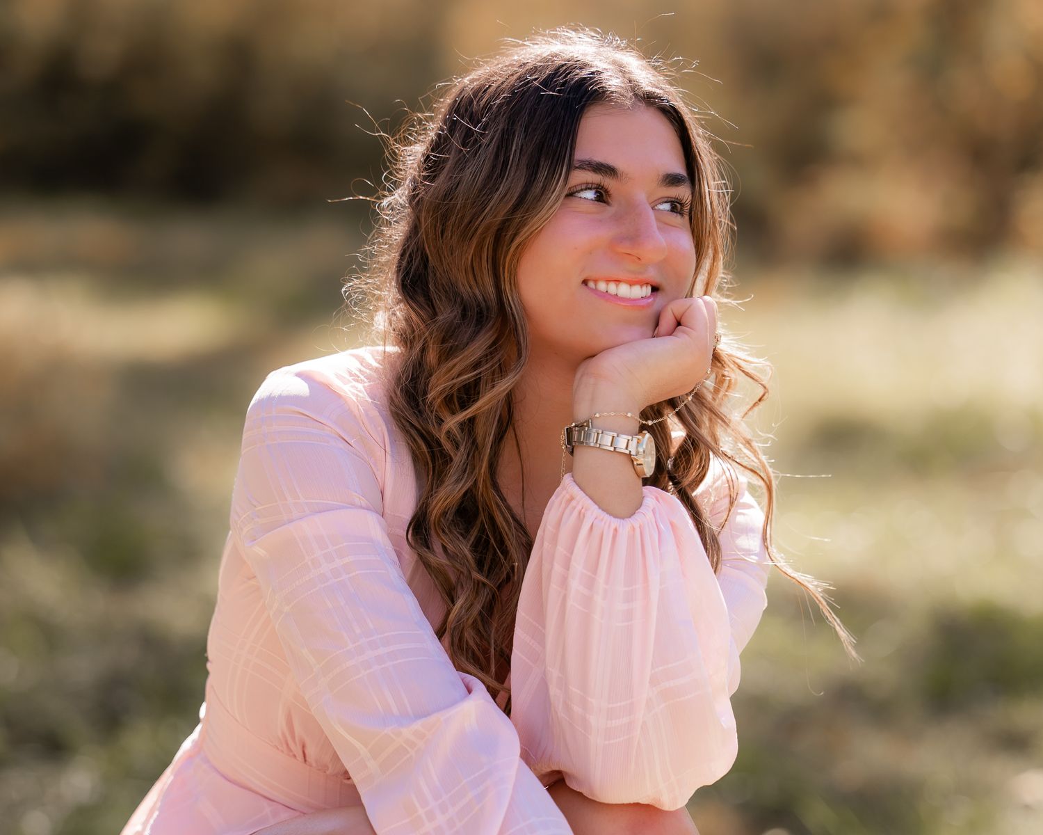 A person in a pink sweater poses outdoors in a series of candid shots with natural lighting and autumn scenery.
