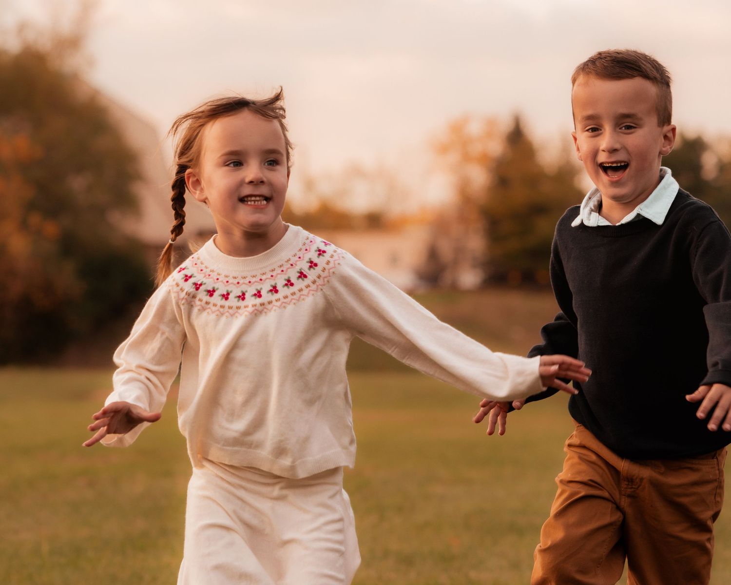 Children playing and running together outdoors during a warm sunset.