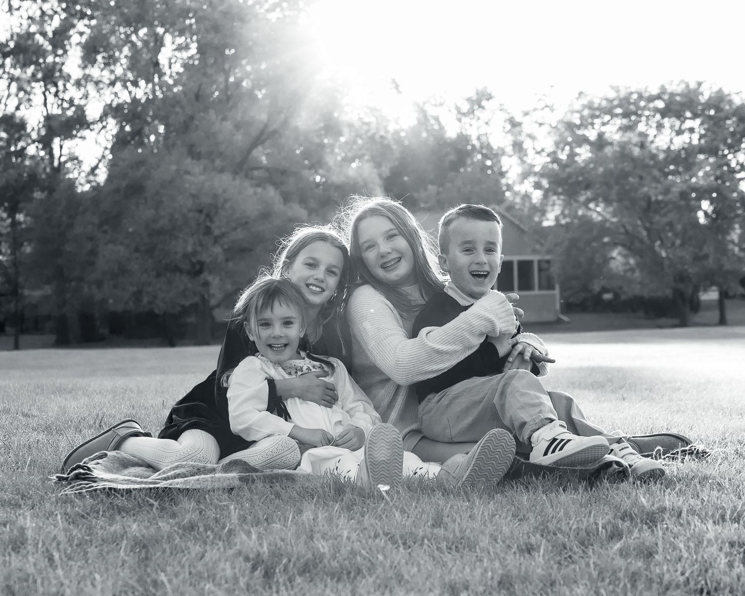 Family lying together on grass in black and white photo series showing playful outdoor moments.