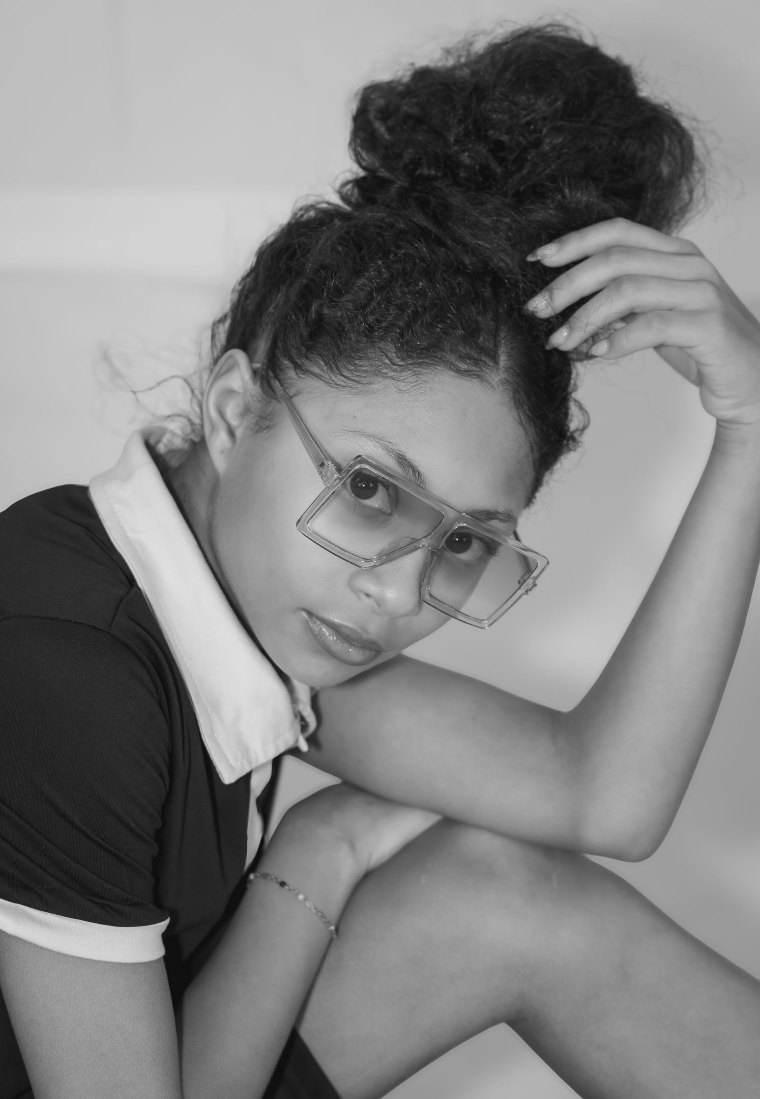 Black and white portrait of a woman with glasses and curly updo in casual attire.