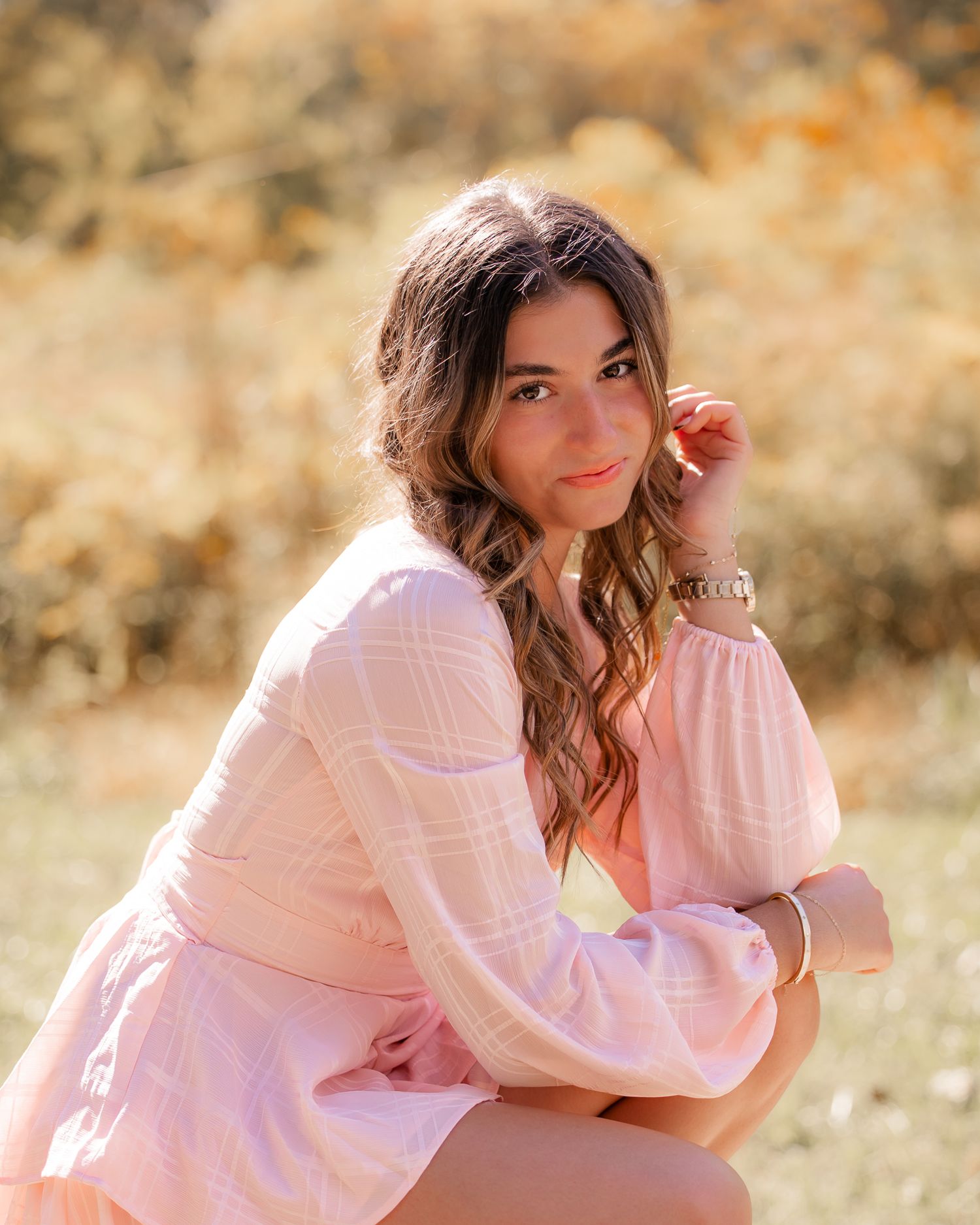 Portrait session in a pink sweater against a warm autumn background.