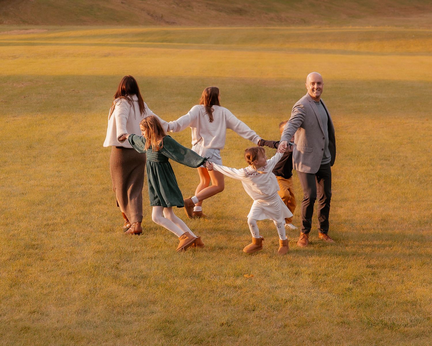 Group plays and interacts in golden field during sunset photoshoot.