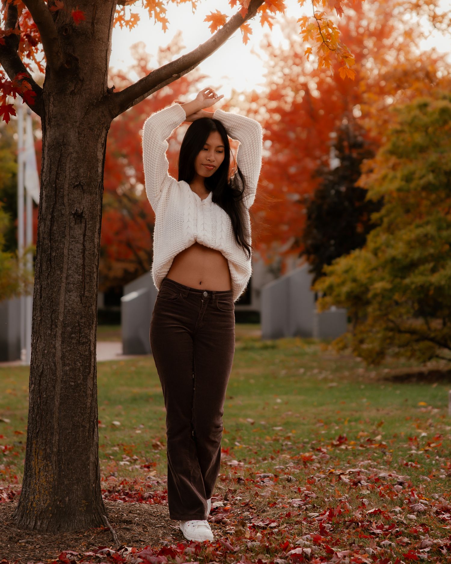 A series of maternity photos showing a pregnant woman in a white dress standing among autumn trees with red leaves.