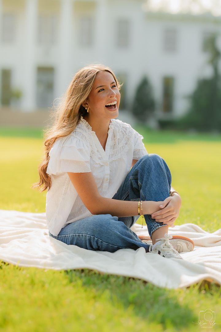 Someone relaxes on a white blanket wearing jeans and a white top during an outdoor photoshoot.