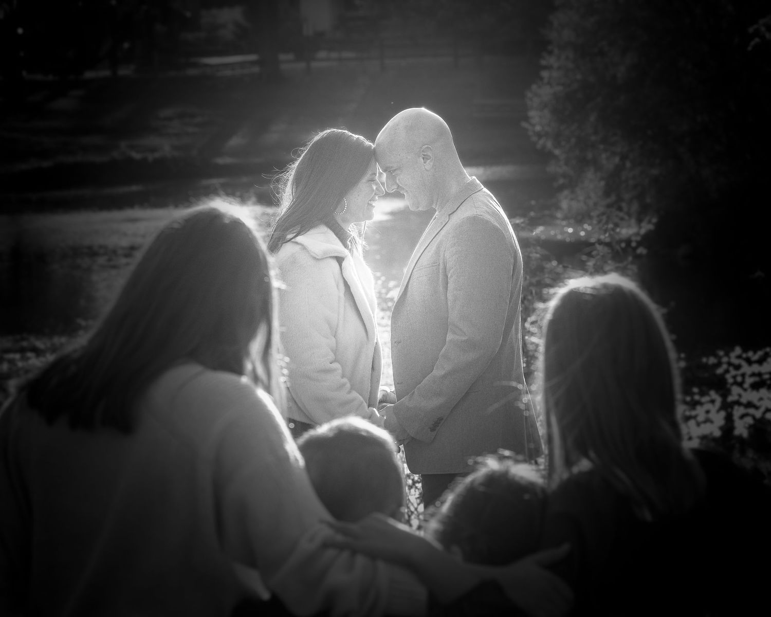 Silhouetted family portrait with dramatic backlighting in black and white.