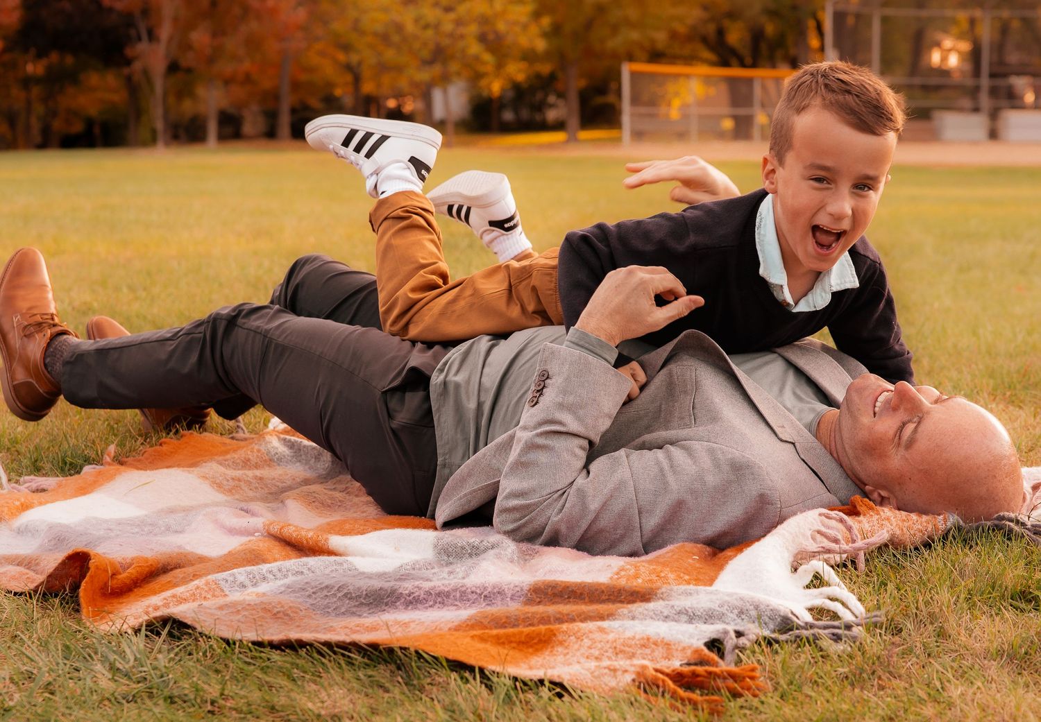 Family lying together on blanket during outdoor autumn photoshoot.