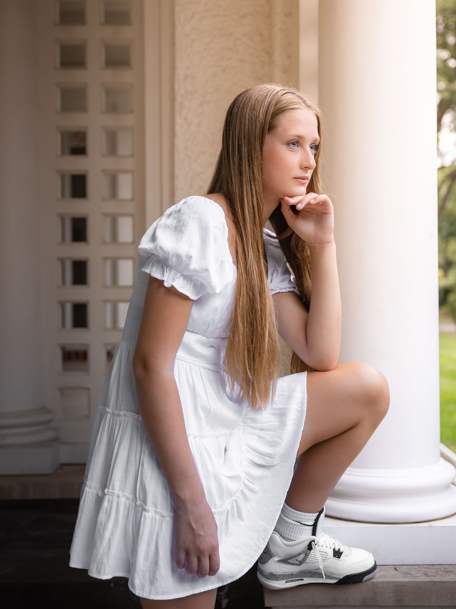 Young woman in white dress sitting thoughtfully on a porch column in a series of contemplative poses.
