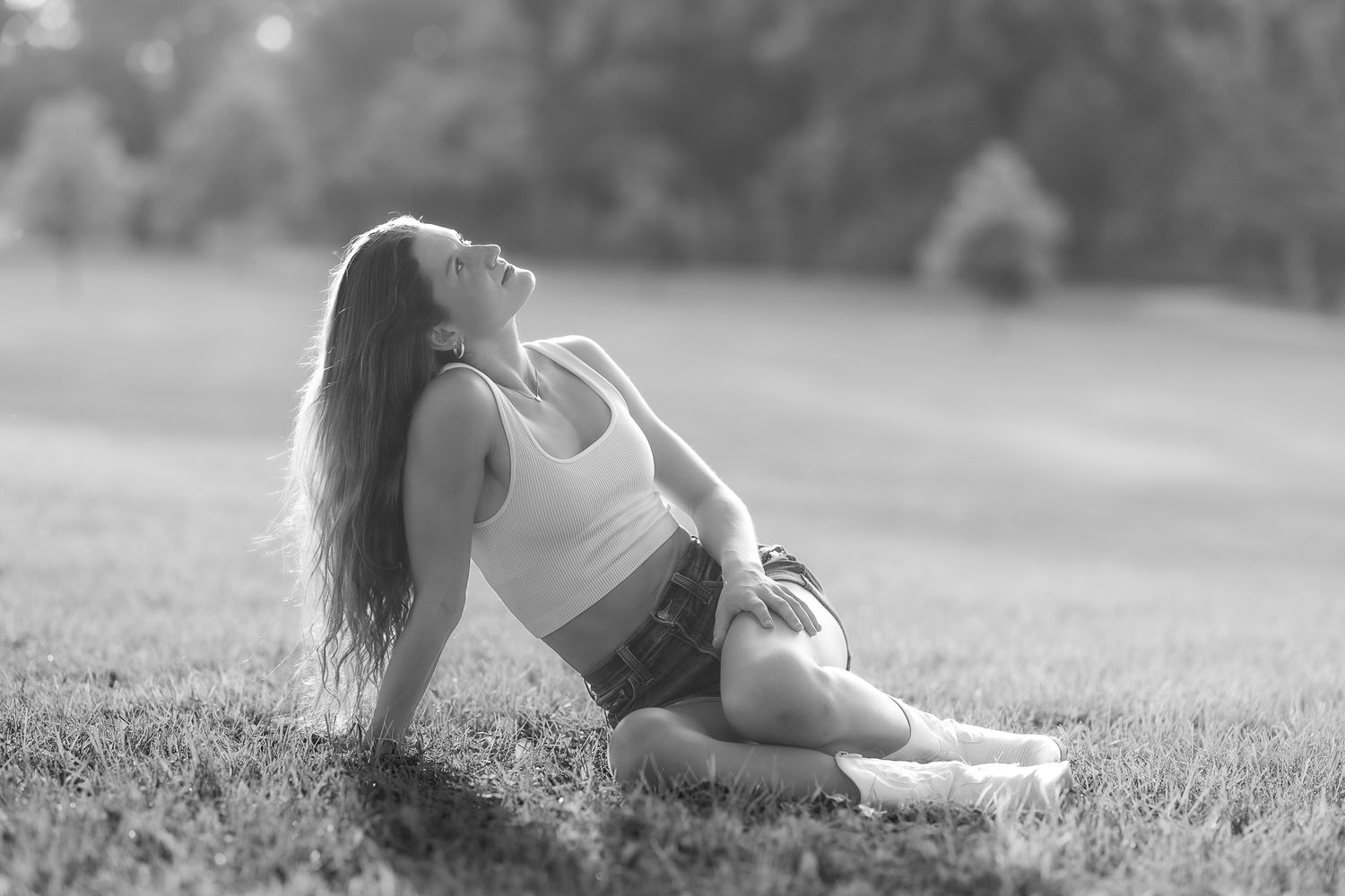 Woman relaxing in grass field during outdoor photo session.