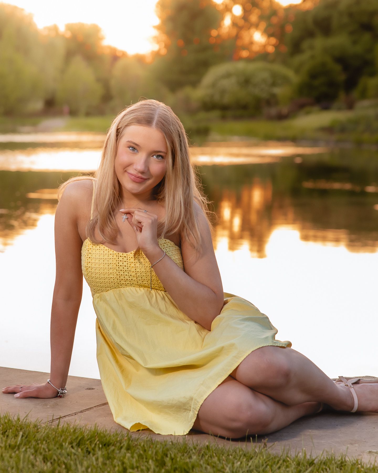 Senior smiling in yellow dress at golden hour by the Cantigny lake