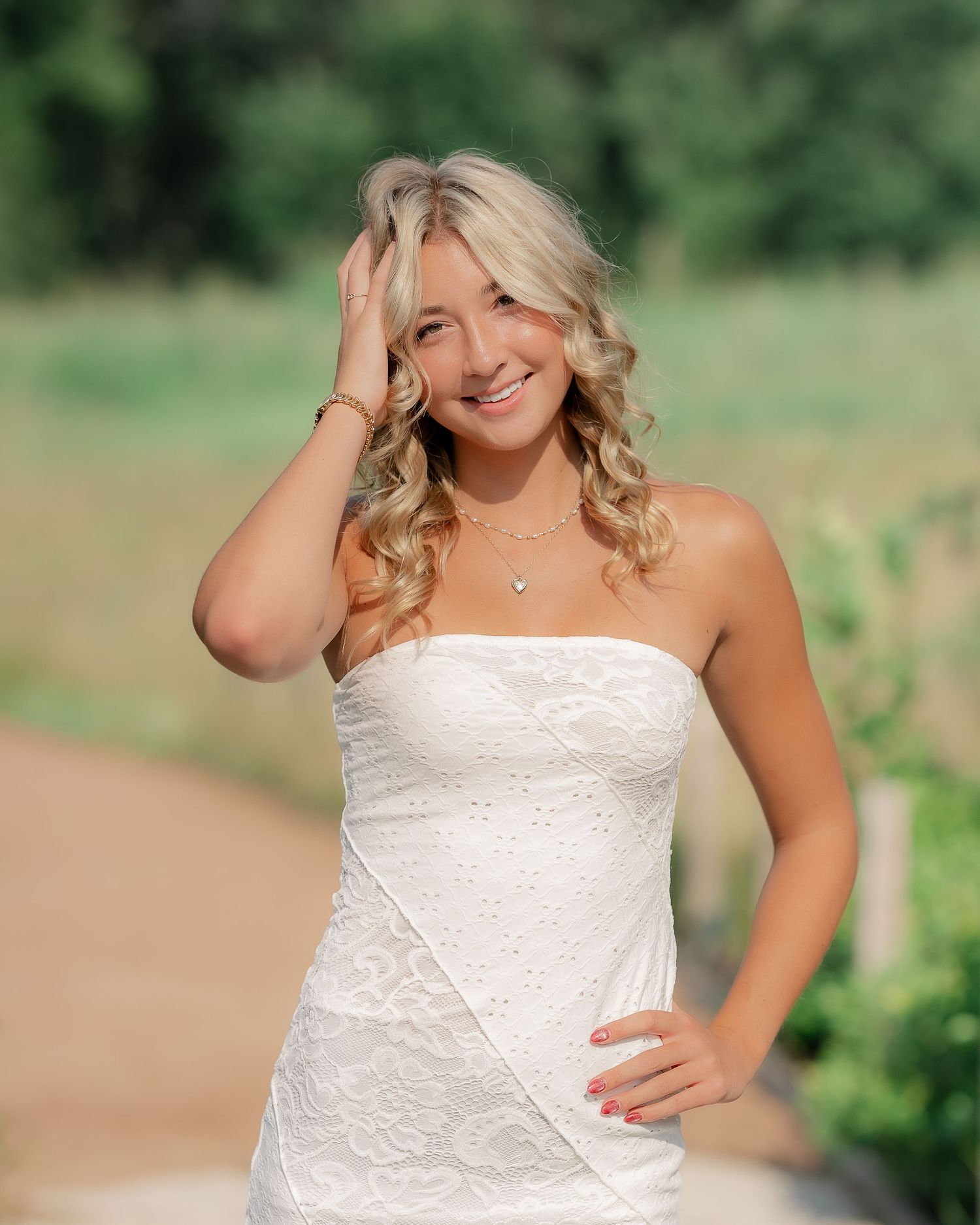 A person in a white lace wedding dress poses outdoors in a natural garden setting with soft lighting and greenery.