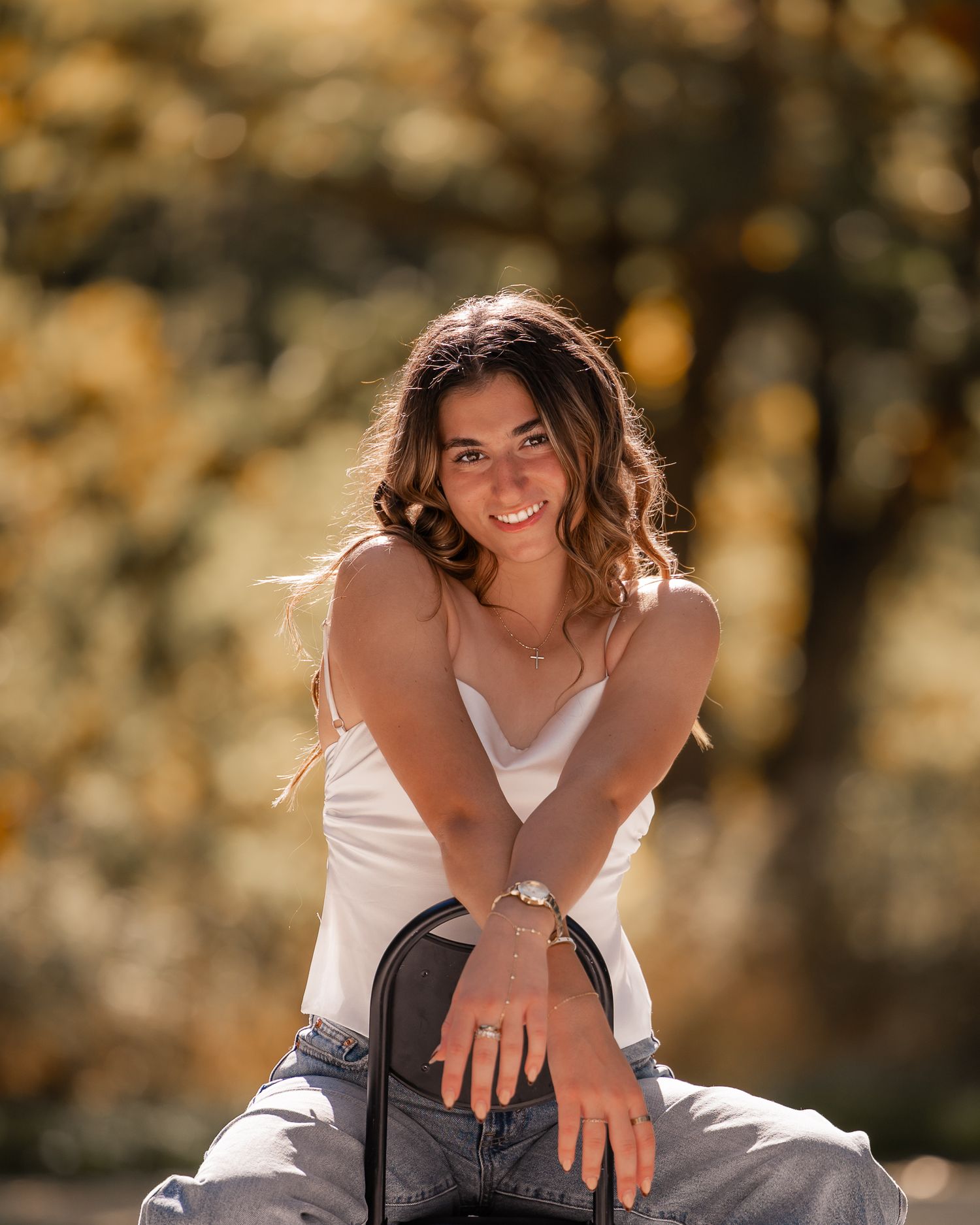 Casual outdoor portrait with white top and natural lighting against blurred autumn background.