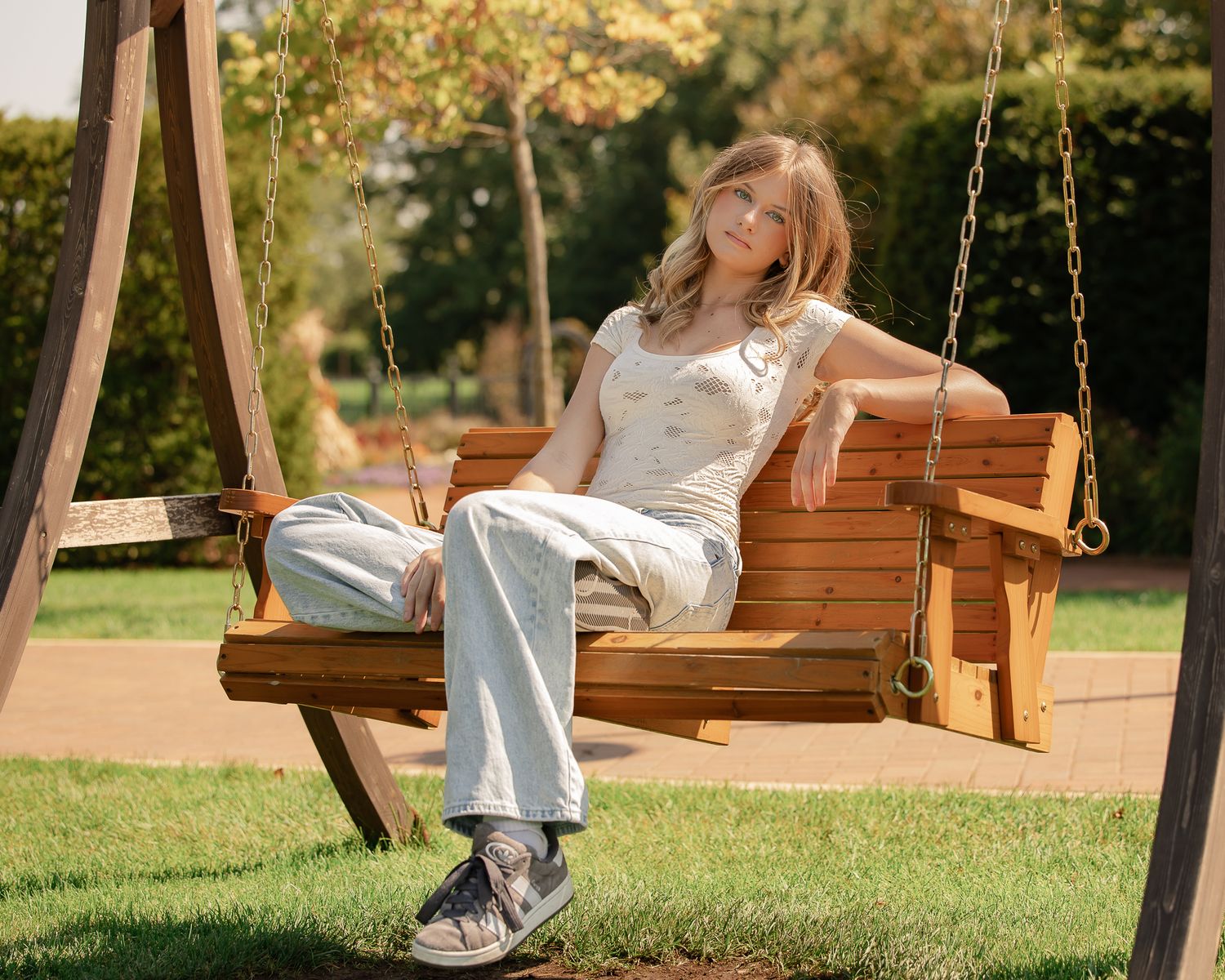 Wooden porch swing in a garden setting with soft natural lighting.