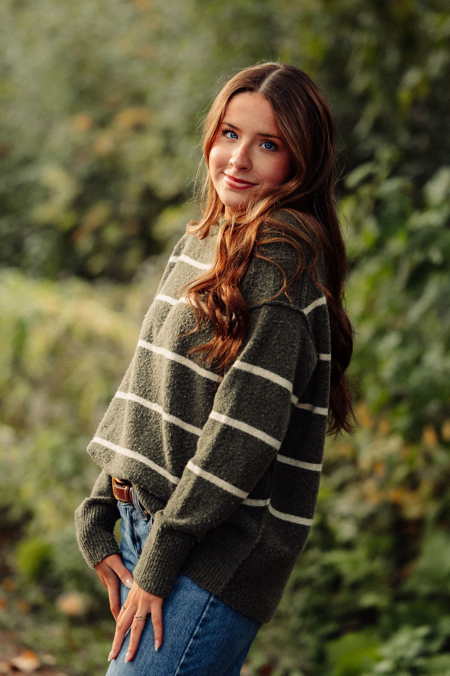 Autumn portrait featuring a striped knit sweater and denim in natural outdoor lighting.