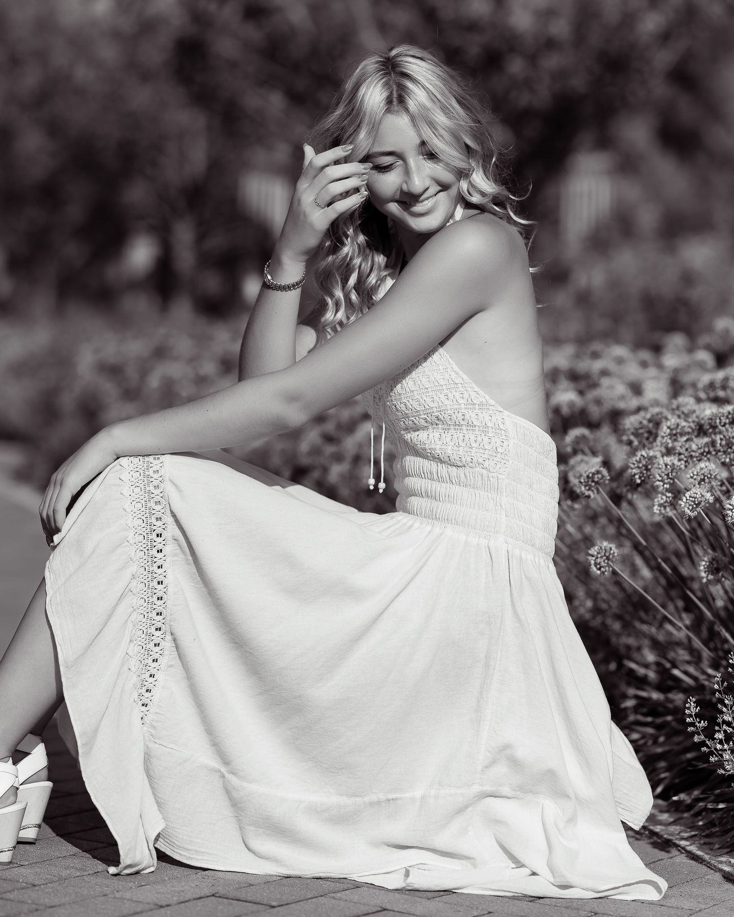 Dreamy black and white portrait in white lace dress among flowers.
